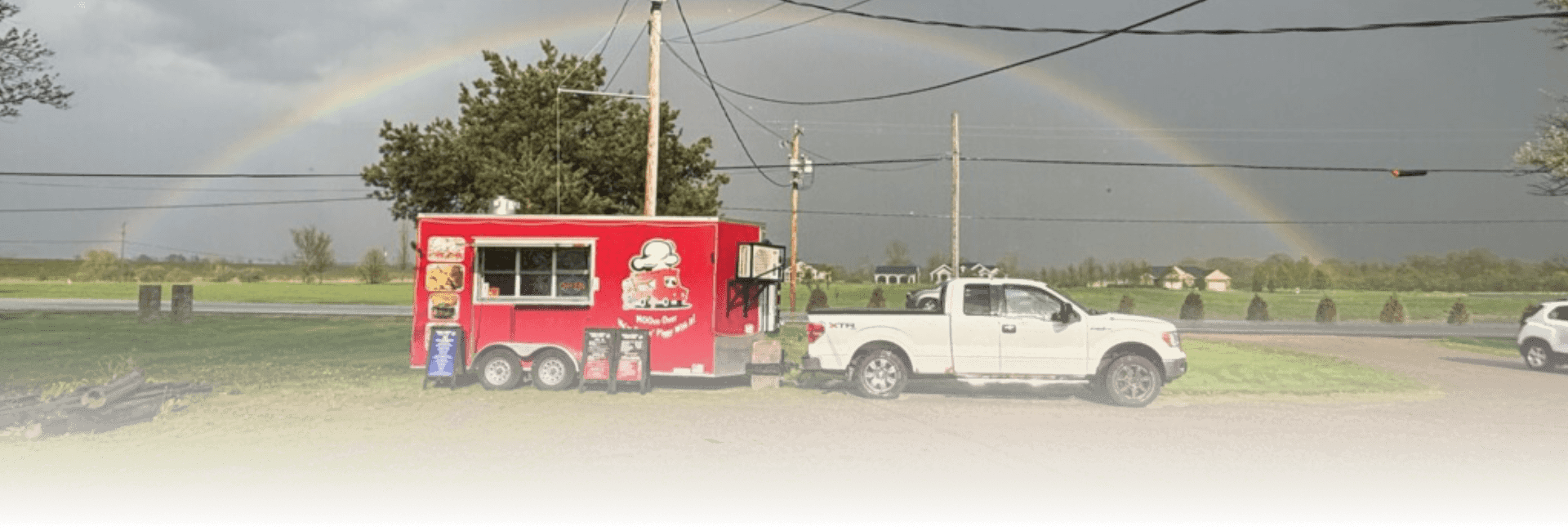 A food truck parked with a rainbow going over top of it